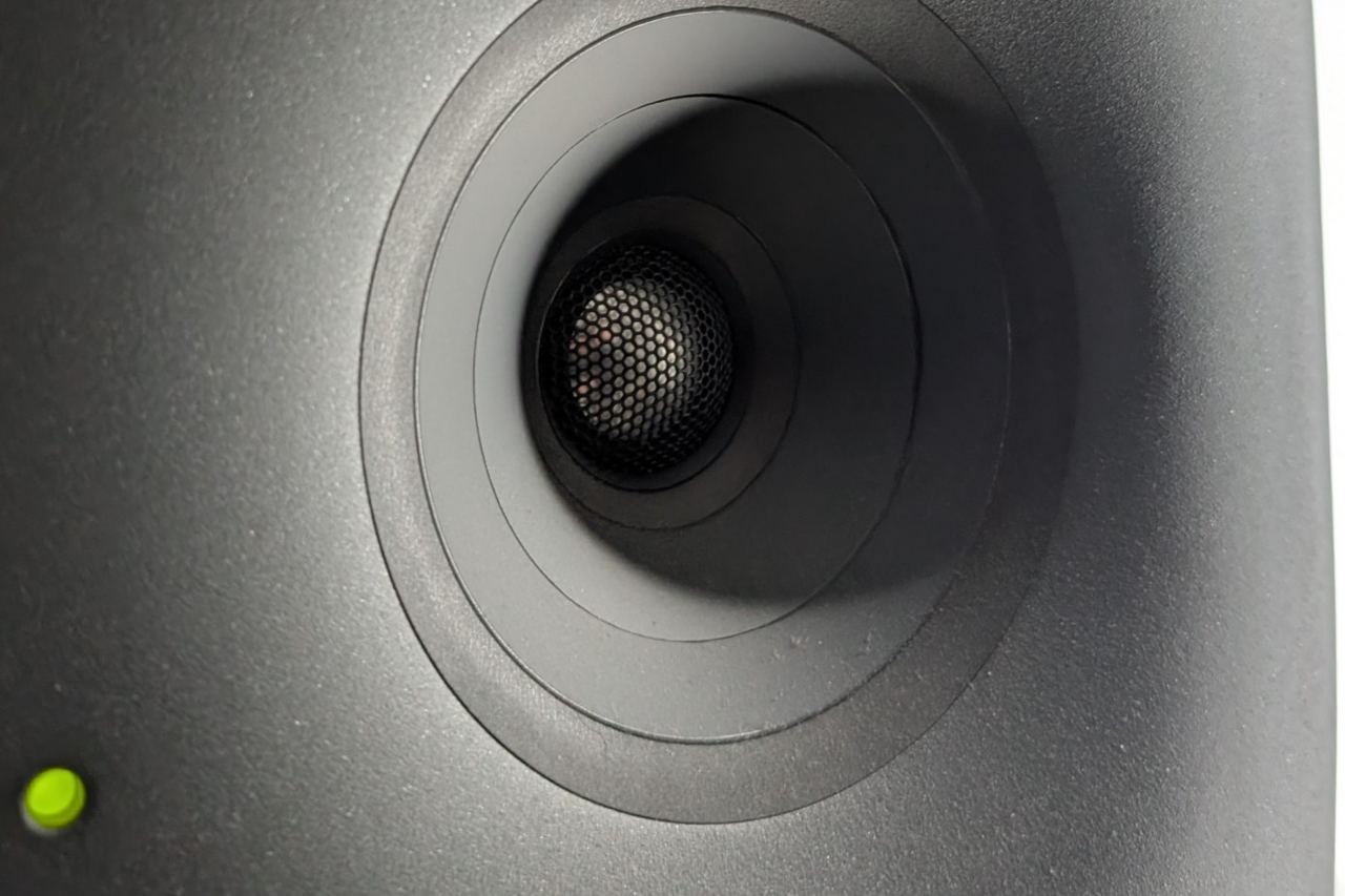 The coaxial driver of a Genelec monitor, close up, its green pilot light on.