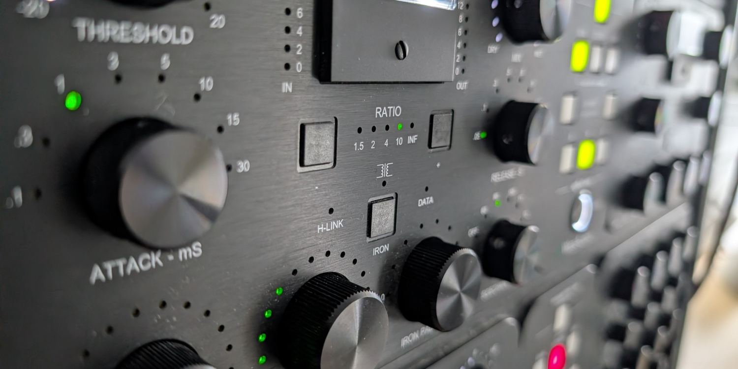 A black outboard compressor seen close up: heavy knobs, a compression meter and green indicator lights.